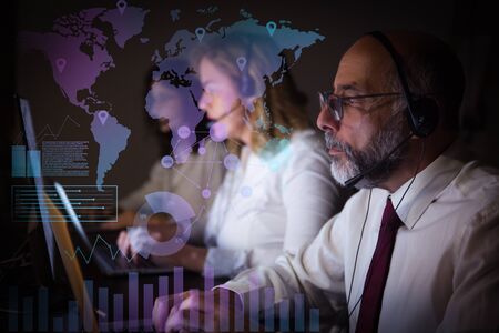 Coworkers in headsets and virtual statistic graphics. Professional focused call center operators in...