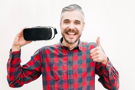 Man holding VR headset and showing thumb up. Happy handsome man using virtual reality headset and...
