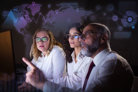Businesspeople in eyeglasses and virtual statistic graphics. Focused mature businessman pointing at...
