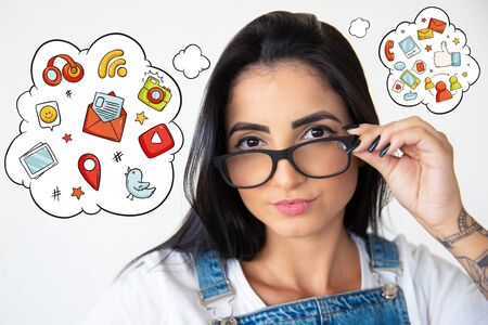Young woman in eyeglasses with hand drawn social media sketches. Attractive young lady holding eyeglasses and looking at camera. Female beauty conceptの写真素材