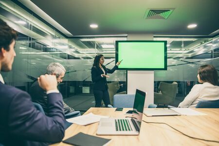 Confident Asian speaker pointing at display. Experienced analyst during presentation. Business conference conceptの写真素材