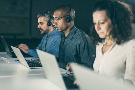 Confident client support team at workplace. Thoughtful call center operators during working process....