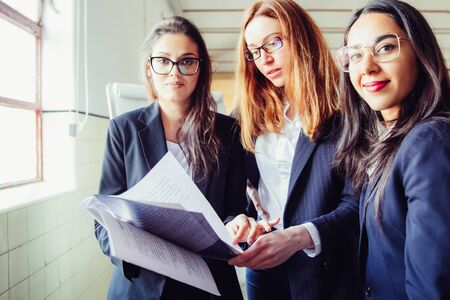 Group of smiling women with paper documents. Front view of professional business team looking at camera. Business conceptの写真素材
