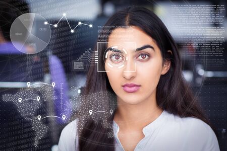 Latin-American businesswoman and virtual identification graphics. Portrait of serious young woman with black hair looking at camera in officeの写真素材