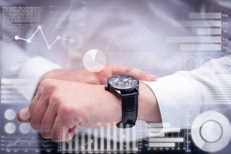 Man checking time with wristwatch and virtual statistic graphics. Caucasian executive waiting for client being late. Time and punctuality conceptの写真素材