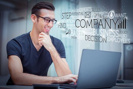 Happy handsome man working on laptop and virtual business text. Closeup portrait of smiling young handsome man working on computer in loungeの写真素材