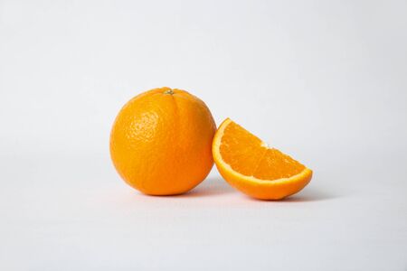 Cut orange section and whole fruit isolated on white background. Closeup shot. Natural vitamin or organic food conceptの写真素材
