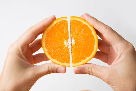 Person connecting cut orange sections isolated on white background. Cropped shot, closeup. Healthy nutrition or organic food conceptの写真素材