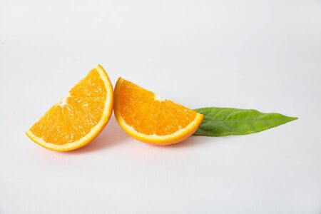 Cut orange sections and green leaf isolated on white background. Closeup shot. Healthy nutrition or organic food conceptの写真素材