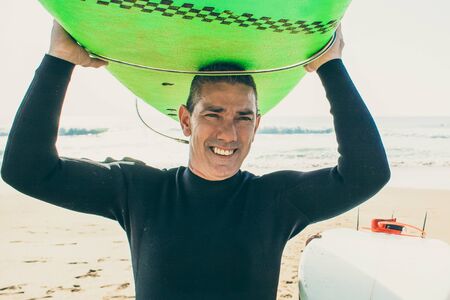 Father and son holding surfboards. Happy father and cute little son in wetsuits holding surfboards on sandy beach. Surfing conceptの写真素材