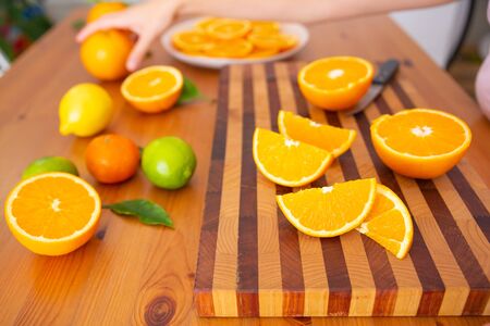 Side view of sliced orange laying on wooden board. Citrus fruits on desk. Hand taking orange on background. Studio shot. Selective focus. Nutrition and vegetarian conceptの写真素材