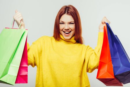 Happy young woman with colorful shopping bags. Cheerful young woman holding colorful paper bags and...