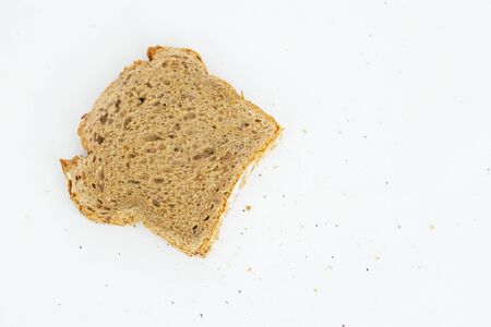 Single sliced piece of rye bread laying at right side and crumbs. Tasty rural loaf slice isolated on...
