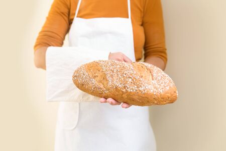 French loaf of freshly baked wheat bread in bakers hand. Closeup of person holding food. Occupation...