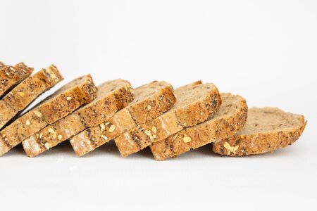 Cropped view of fresh loaf with poppyseeds cutting on slices. Sliced bread with cereals made of rye flour isolated on white background. Studio shot. Side view. Homemade food and nutrition conceptの写真素材