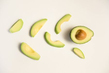 Slices and half of avocado fruit. Creative flat lay, top view. Isolated object on white background....
