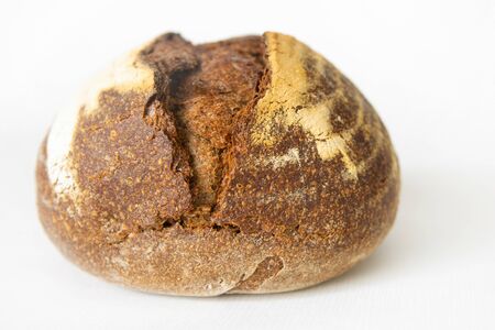 Delicious rye bread baked at home. Crispy round dark loaf isolated on white background. Studio shot....