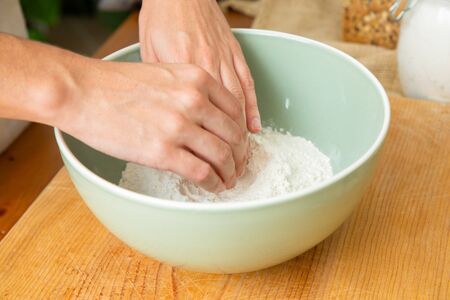 Hands touching wheat flour in ceramic bowl. Dough preparation for delicious pastry. Studio shot....