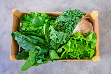 Wooden box with fresh green lettuce, celery, parsley on floor. Top view. Healthy eating or fresh market delivery service conceptの写真素材