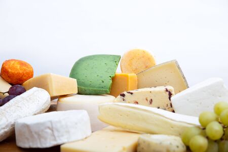 Heap of green, white and spicy cheeses and snacks, whole and cut pieces. Closeup, side view, copy space. Cheese dairy conceptの写真素材