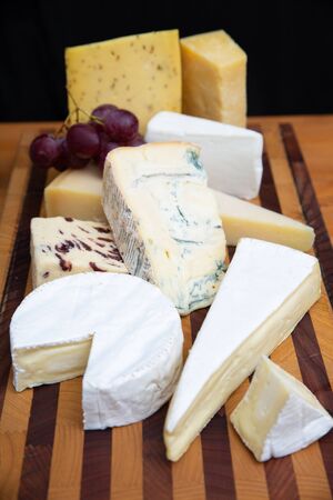 Different cheeses laying on wooden board. Brie, camembert, parmesan collection. Studio shot....