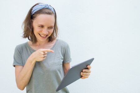 Happy cheerful young woman using tablet for video talk, speaking and gesturing at display, pointing...