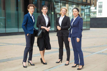 Happy successful female business group standing together near office building, posing, looking at camera and smiling. Full length, front view. Businesswomen group portrait conceptの写真素材