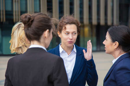 Female colleagues meeting at office building and talking. Businesswomen wearing suits standing together in city. Work discussion and business colleagues conceptの写真素材