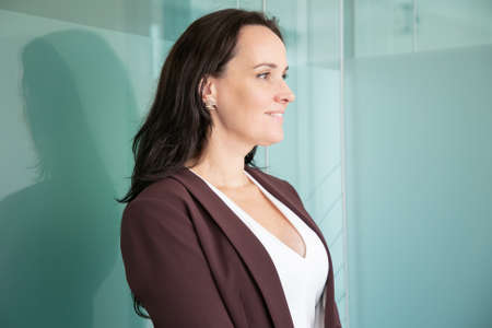 Beautiful middle-aged businesswoman standing and looking away. Caucasian professional female office...