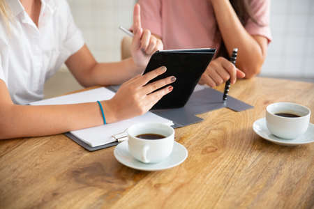 Business ladies meeting at table, watching presentation on tablet, discussing project or deal....