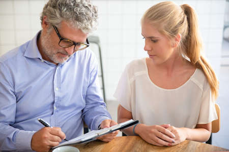 Businessman meeting with agent at co-working, writing in paper, completing and signing agreement...