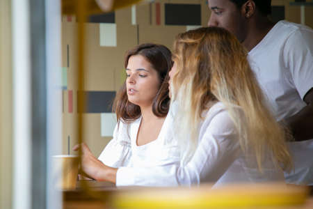 Cropped view of multiethnic designers discussing project. Caucasian women meeting, sitting and...