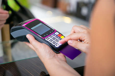 Shop cashier operating payment process with pos terminal and credit card. Cropped shot, closeup of...