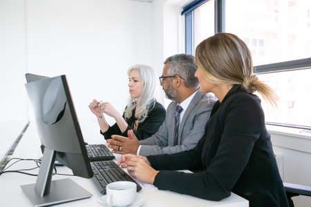 Company managers meeting. Team of professionals sitting at workplace with monitors together and...
