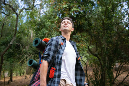 Hiking man looking at nature landscape. Attractive Caucasian young tourist with backpack enjoying...