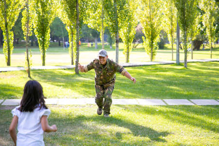 Happy military father meeting with daughter after mission trip. Girl running to dad wearing...