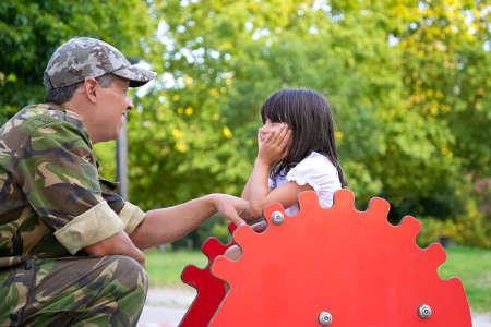 Happy military dad enjoying time with little daughter in playground, talking and playing with girl...