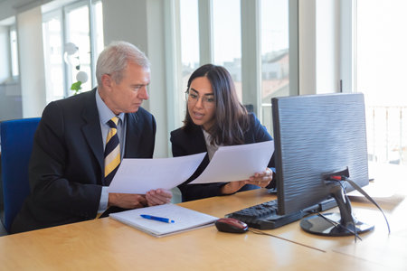 Consultant explaining document details to client at workplace. Serious business leader consulting financial or legal expert. Teamwork or cooperation conceptの写真素材