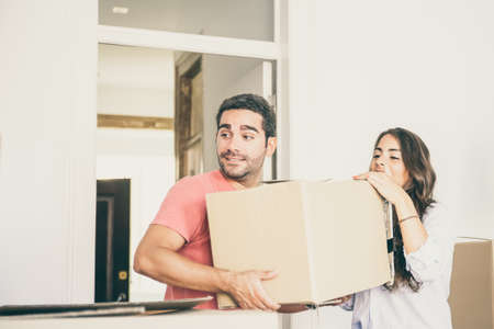 Young couple moving into new house, carrying carton boxes. Medium shot. Real estate or property buying conceptの写真素材