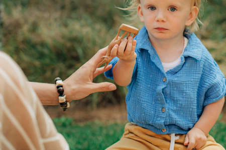 Close-up of little girl holding wooden figurine of deer, her mother sitting by her. Mother and child...