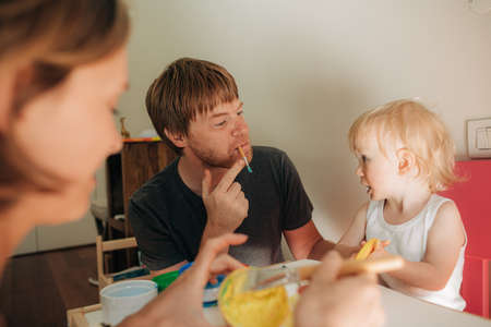 Joyful father painting with his little daughter. Family with toddler spending time together at home. Family leisure conceptの写真素材