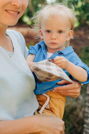 Portrait of cute toddler girl in mothers arms. Happy mid adult woman walking with little daughter outdoors. Childhood conceptの写真素材