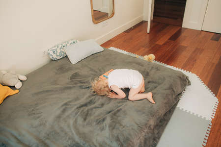 Upset baby girl lying on sofa alone. Toddler hiding her face or crying in room. Naughty child conceptの写真素材