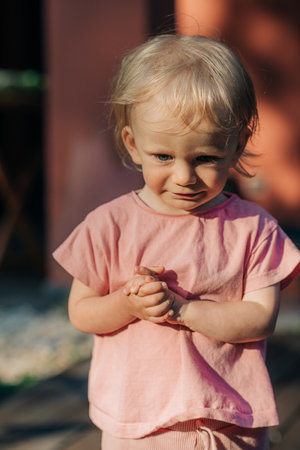 Portrait of upset little girl standing outdoors. Cute toddler wearing pink tshirt. Childhood conceptの写真素材