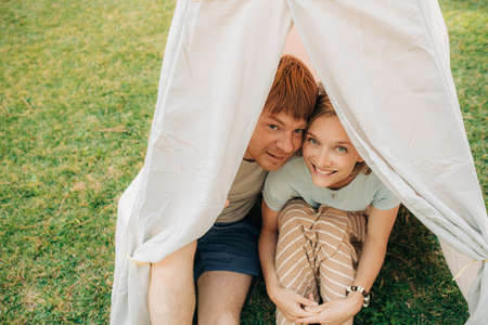 Portrait of happy mid adult couple sitting in tent, looking at camera and smiling outdoors. Cheerful man and woman resting together in park. Weekend, relationship conceptの写真素材