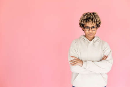 Frowning African American woman showing dislike. Female model in glasses with curly hair with crossed arms, looking at camera. Portrait, emotion, studio shot conceptの写真素材