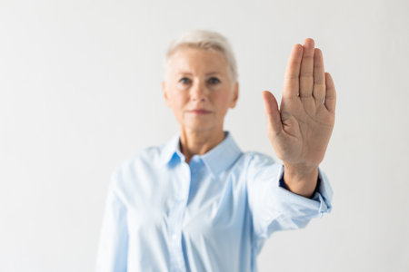 Portrait of senior woman expressing refusal. Female model in blue shirt rejecting something with serious face. Portrait, studio shot, refusal conceptの写真素材