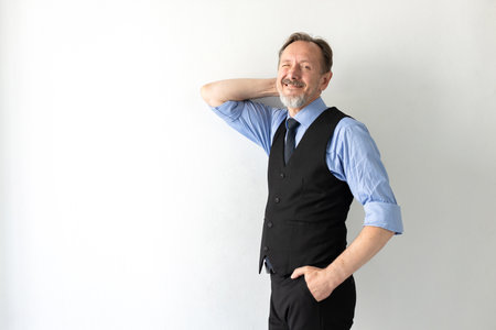 Portrait of happy mature businessman posing in studio. Senior Caucasian manager wearing formalwear standing with hand in pocket, winking and smiling. Successful businessman conceptの写真素材