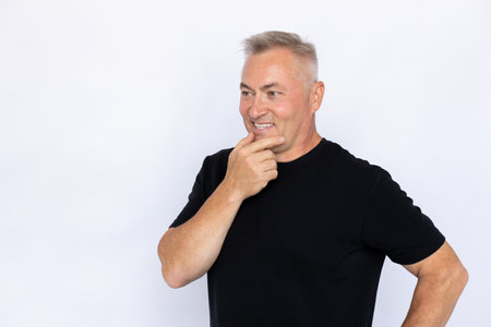 Portrait of thoughtful senior man smiling. Pensive Caucasian male model in black T-shirt with gray...