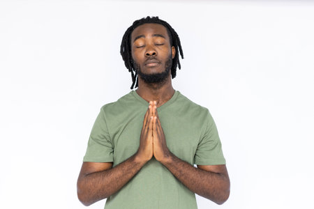 Portrait of calm African American man pressing hands together. Thoughtful young male model with...